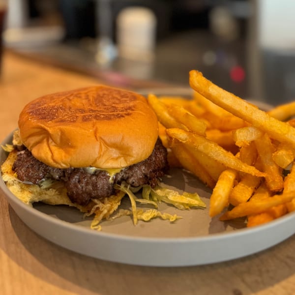 A juicy burger with melted cheese and shredded lettuce, served with golden french fries on a gray plate.